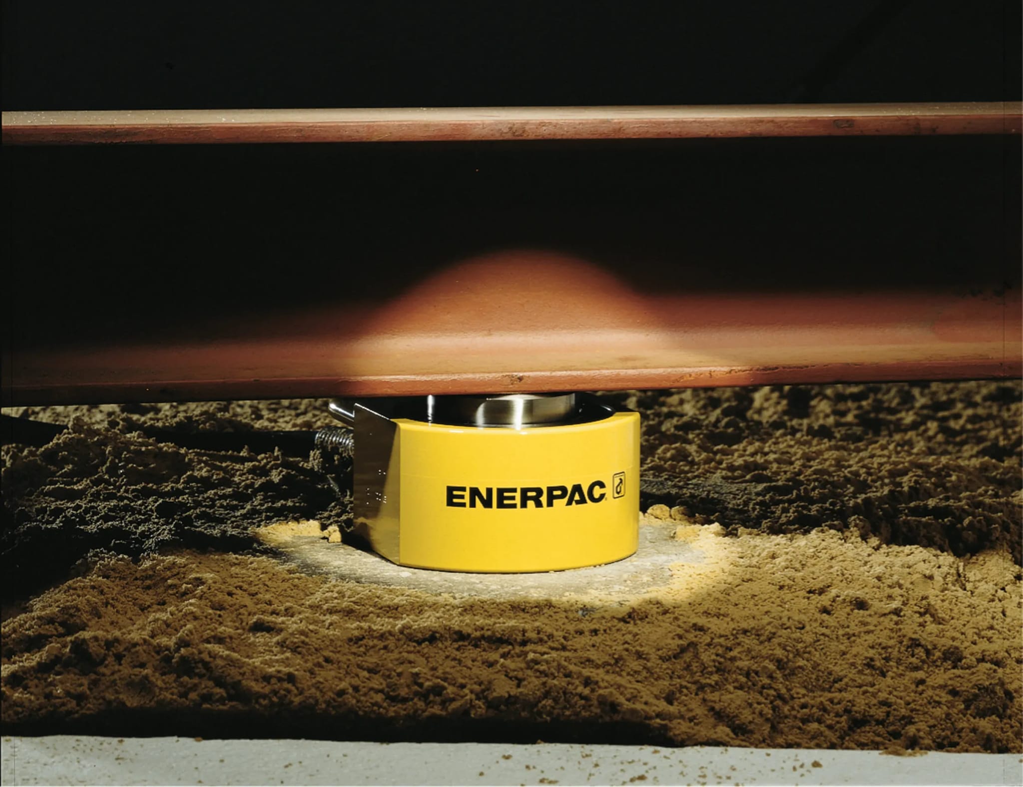 Flachzylinder unter einer Eisenbahnschiene.